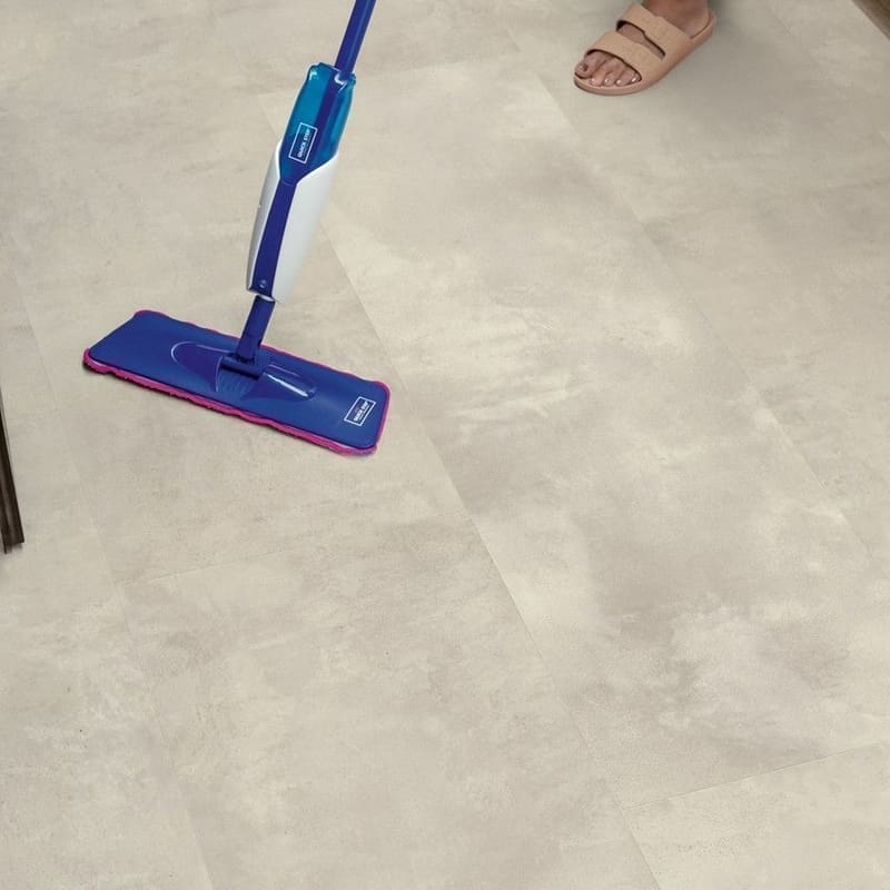Close-up of person mopping Quick-Step Muse Stained Concrete flooring demonstrating water resistance