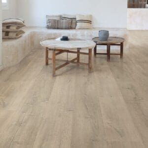 Quick-Step Patina Oak Brown laminate installed in a minimalist living area with neutral furniture