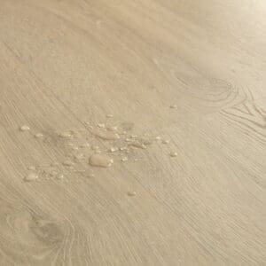 Full room installation of Quick-Step Classic Sandy Greige Oak laminate flooring in a living space with wooden furniture