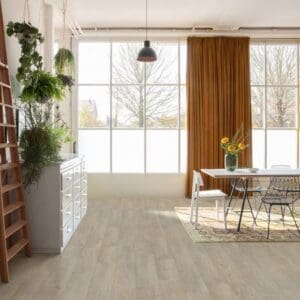 Bright dining area with Quick-Step Classic Old Oak Light Grey laminate flooring, large windows and plants