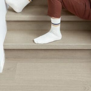 Person sitting on stairs with Quick-Step Alpha Blos Chia Oak flooring