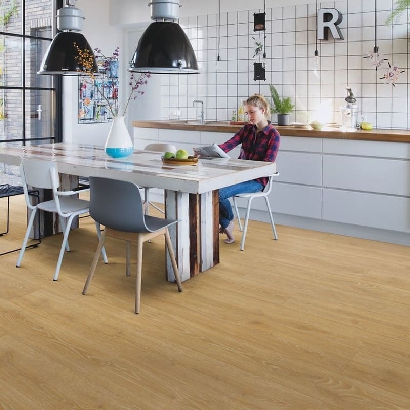 Modern kitchen with Quick-Step Majestic Woodland Oak Natural laminate flooring installed, showing warm oak tones complementing contemporary design