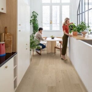 Modern kitchen with Quick-Step Alpha Blos Coast Oak Sand flooring installed showing bright, airy space