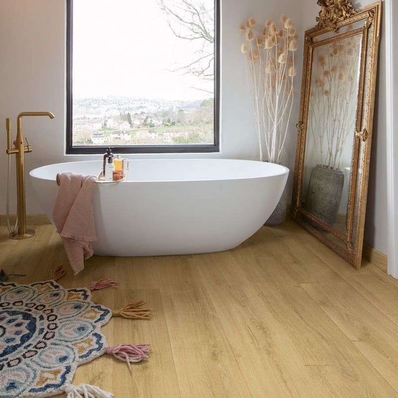 Quick-Step Capture Brushed Oak Warm Natural laminate flooring in a kitchen with a person in blue dress