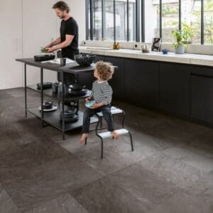 Modern kitchen with Quick-Step Muse Grey Slate Laminate flooring and child sitting on step stool
