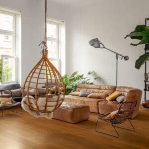 Close-up of person's feet on Quick-Step Capture Merbau SIG4760 laminate flooring with leather bag on wooden bench
