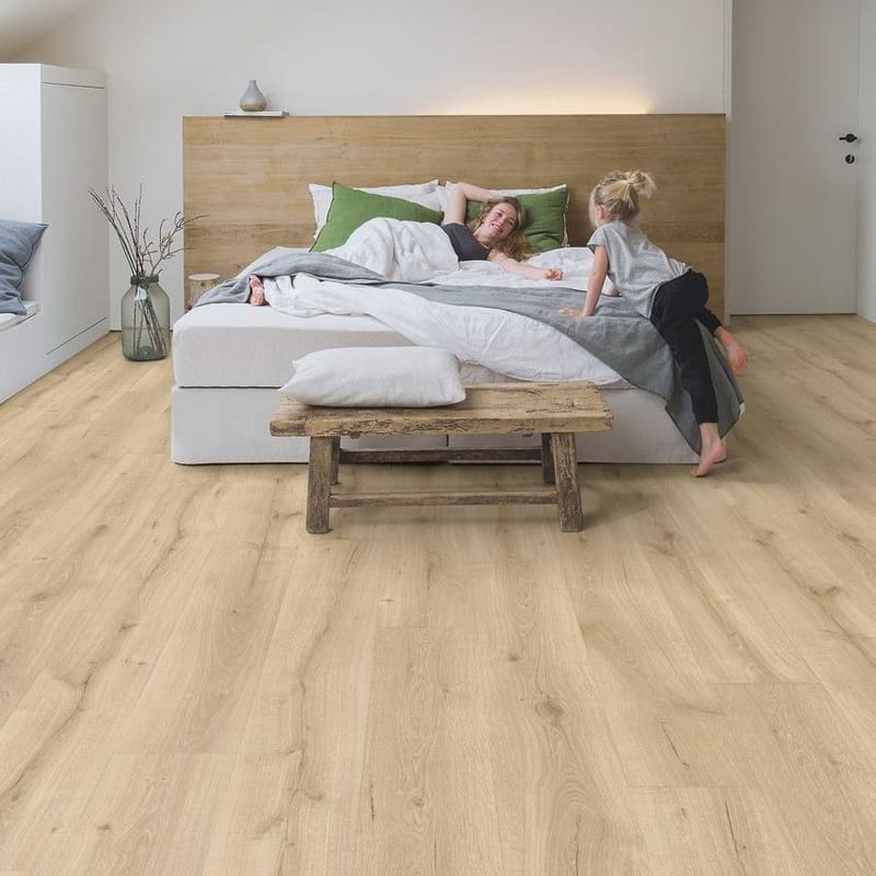 Quick-Step Majestic Desert Oak Light Natural laminate flooring installed in a bright attic bedroom with wooden beams and minimalist decor
