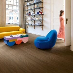 Modern living room featuring Quick-Step Capture Chic Walnut laminate flooring with blue and yellow furniture