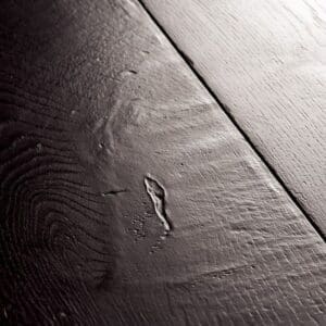 Close-up of black laminate flooring showing wood grain texture and beveled edge