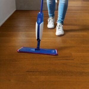 Person cleaning Quick-Step Capture Merbau SIG4760 laminate flooring with a blue mop, showing ease of maintenance