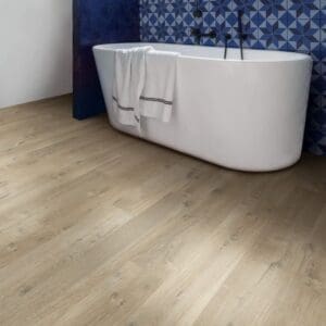 Quick-Step Impressive Ultra Soft Oak Light Brown laminate installed in a modern bathroom with blue accent wall and freestanding bathtub