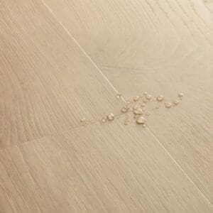Detail of Quick-Step Alpha Blos Coast Oak Sand showing water droplets demonstrating waterproof properties