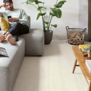 White rocking chair with blue cushion on white laminate flooring next to window