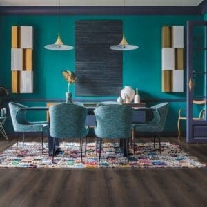 Quick-Step Majestic Desert Oak Brushed Dark Brown laminate flooring installed in a modern dining room with teal walls
