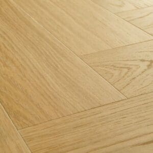 Close-up detail of Quick-Step Alpha Ciro Pure Oak Honey vinyl flooring showing herringbone pattern and wood grain texture