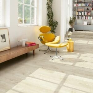 Quick-Step Canyon Oak Beige flooring installed in a modern living room with yellow chair and bookshelf
