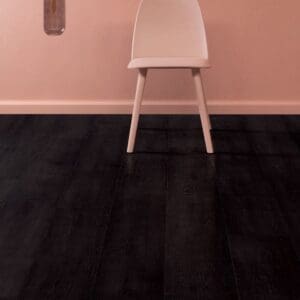 Pink chair against pink wall with black laminate flooring showing contrast