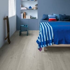 Quick-Step Alpha Bloom Cotton Oak Cold Grey flooring installed in a modern blue bedroom with built-in shelving