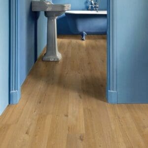 Hallway with Quick-Step Soft Oak Natural laminate flooring leading to bathroom with plants and white tile walls