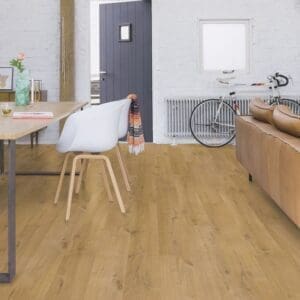 Quick-Step Impressive Soft Oak Natural laminate flooring installed in a modern living room with wooden dining table and white chairs