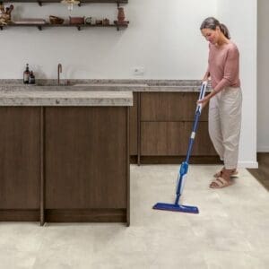 Woman mopping Quick-Step Muse Stained Concrete flooring in kitchen showing easy maintenance