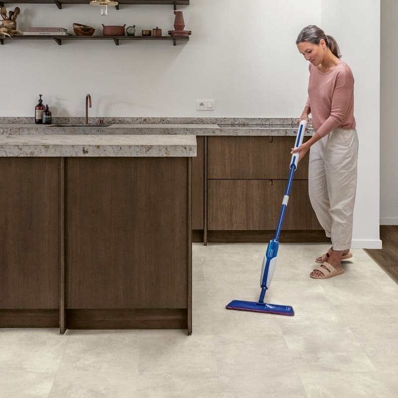 Woman mopping Quick-Step Muse Stained Concrete flooring in kitchen showing easy maintenance