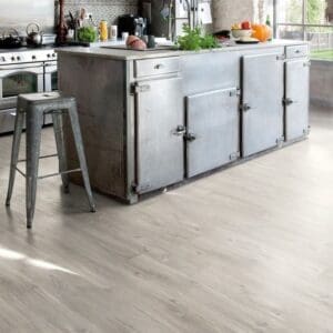 Quick-Step Canyon Oak Grey vinyl flooring installed in an industrial-style kitchen with metal island