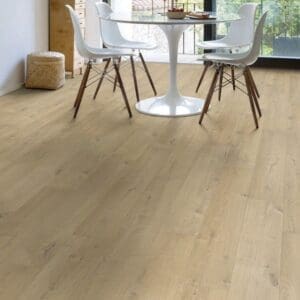 Modern dining area with white table and chairs on Quick-Step Soft Oak Medium laminate flooring