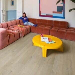 Contemporary living space with coral sectional sofa and modern art on Quick-Step Soft Oak Medium flooring
