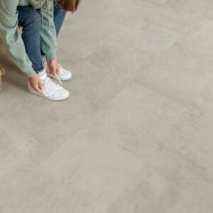 Person mopping Quick-Step Grey Concrete Laminate flooring in kitchen, demonstrating water resistance
