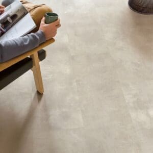 Person relaxing in chair with coffee and magazine on Quick-Step Muse Stained Concrete flooring