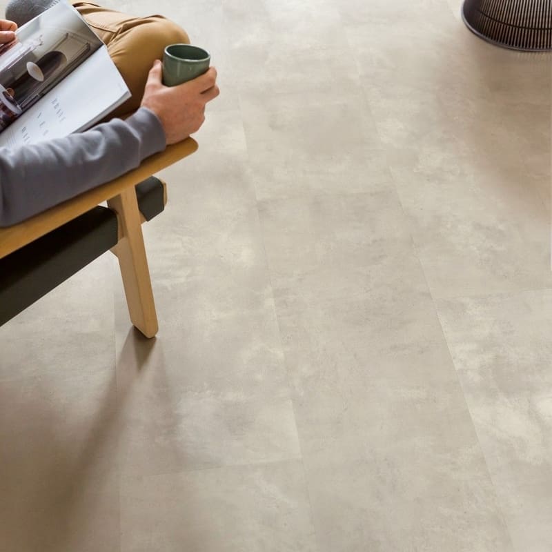 Person relaxing in chair with coffee and magazine on Quick-Step Muse Stained Concrete flooring