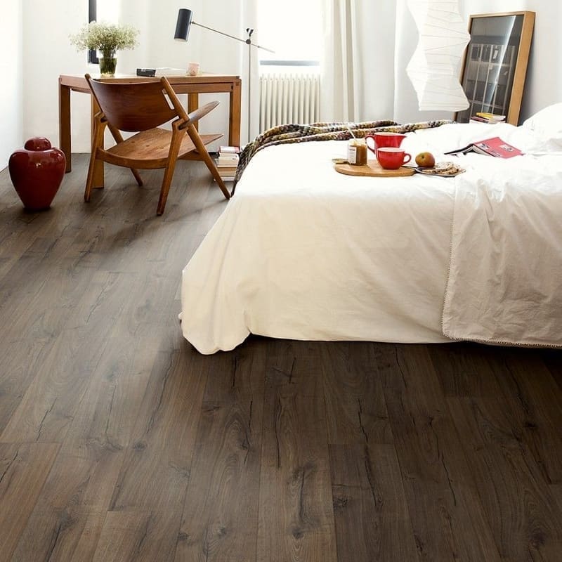 Bedroom interior featuring Quick-Step Impressive Classic Oak Brown laminate flooring with wooden furniture and white decor