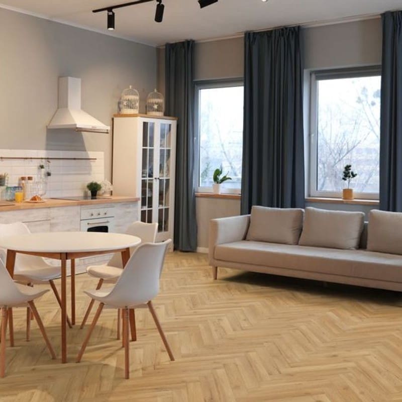 Open plan living space with oak herringbone flooring featuring kitchen and sofa area